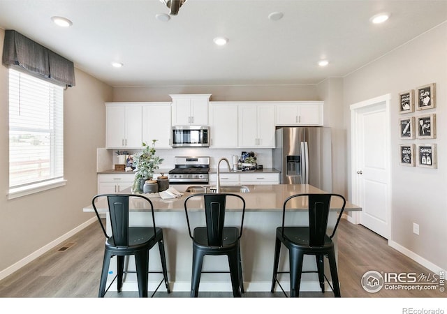 kitchen featuring a sink, decorative backsplash, a kitchen bar, and stainless steel appliances