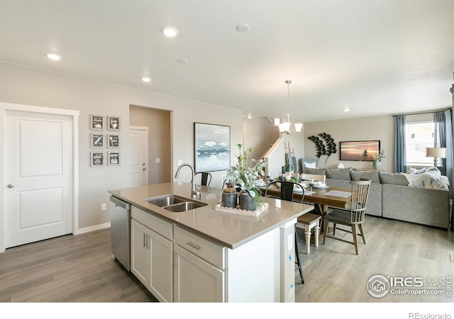 kitchen featuring open floor plan, light wood-type flooring, stainless steel dishwasher, and a sink