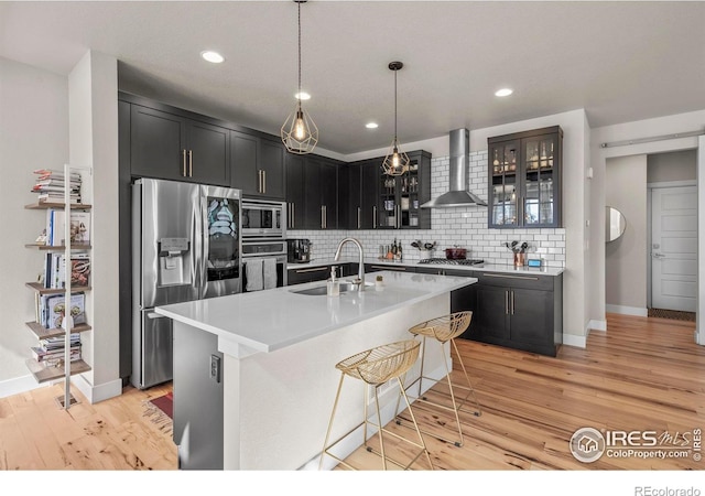 381 Pilsner St, Fort Collins, CO 80524 - kitchen with wall chimney exhaust hood, glass insert cabinets, a sink, stainless steel appliances, and dark cabinetry