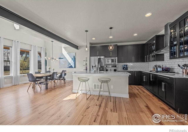 381 Pilsner St, Fort Collins, CO 80524 - kitchen featuring wall chimney exhaust hood, dark cabinets, appliances with stainless steel finishes, a breakfast bar area, and backsplash