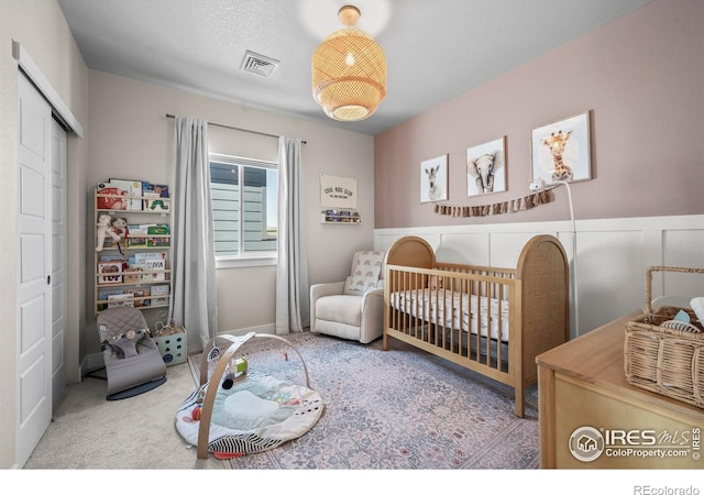 381 Pilsner St, Fort Collins, CO 80524 - carpeted bedroom with a nursery area, a closet, wainscoting, and visible vents