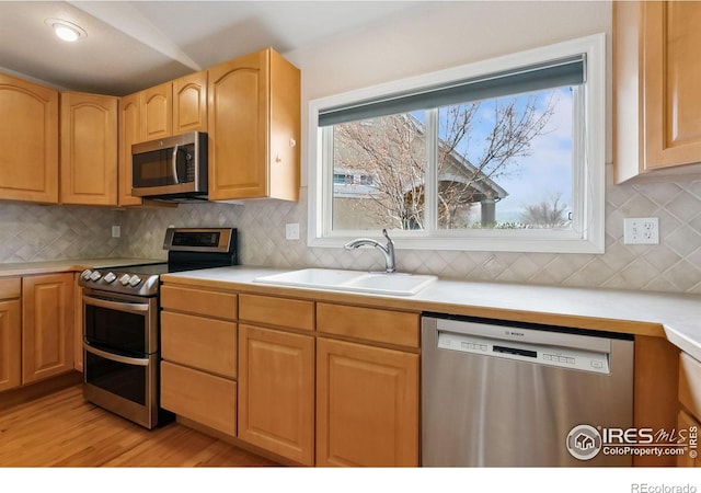 7747 Promontory Dr, Windsor, CO 80528 - kitchen with appliances with stainless steel finishes, a sink, light countertops, light wood-style flooring, and backsplash