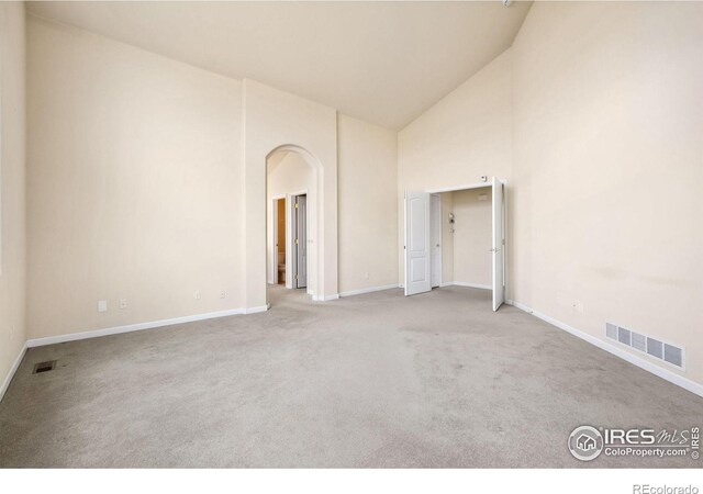 7747 Promontory Dr, Windsor, CO 80528 - spare room featuring high vaulted ceiling, carpet, arched walkways, and baseboards
