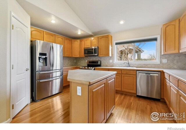 7747 Promontory Dr, Windsor, CO 80528 - kitchen featuring stainless steel appliances, a sink, lofted ceiling, light wood-style floors, and light countertops