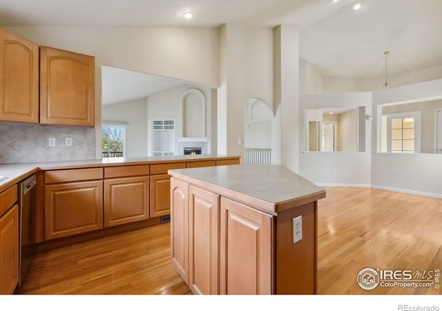 7747 Promontory Dr, Windsor, CO 80528 - kitchen featuring a warm lit fireplace, light wood-style flooring, stainless steel dishwasher, high vaulted ceiling, and tasteful backsplash