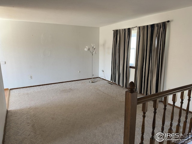 carpeted spare room featuring baseboards