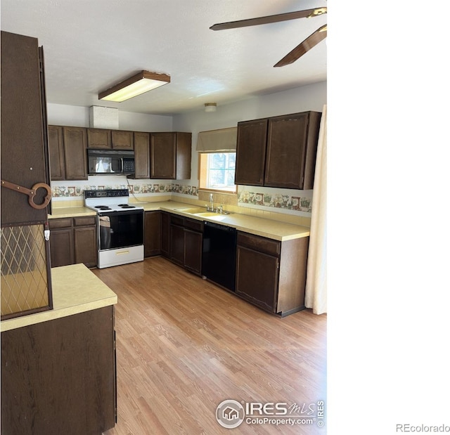kitchen featuring dark brown cabinets, light countertops, black appliances, and a sink