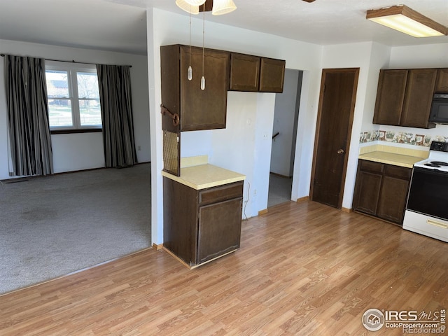 kitchen with electric stove, light countertops, dark brown cabinetry, and light wood finished floors