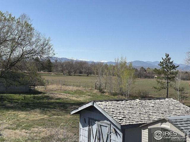 exterior space featuring a rural view, a mountain view, and fence