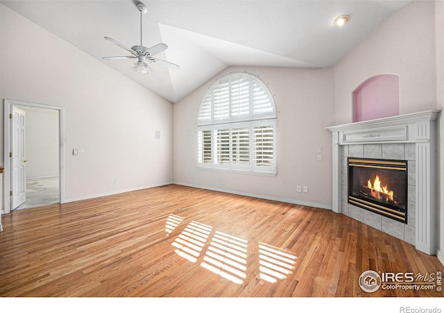 unfurnished living room with baseboards, ceiling fan, wood finished floors, vaulted ceiling, and a tile fireplace