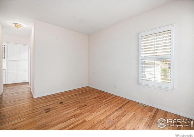 unfurnished room featuring light wood-type flooring, baseboards, and visible vents