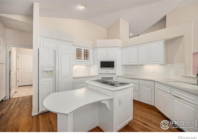 kitchen with white cabinets, a center island, black electric cooktop, a sink, and light countertops