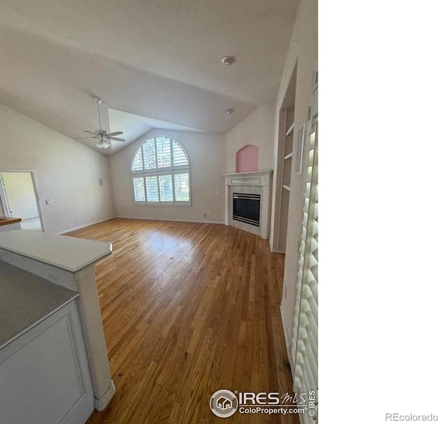 unfurnished living room with wood finished floors, a fireplace, a ceiling fan, and vaulted ceiling