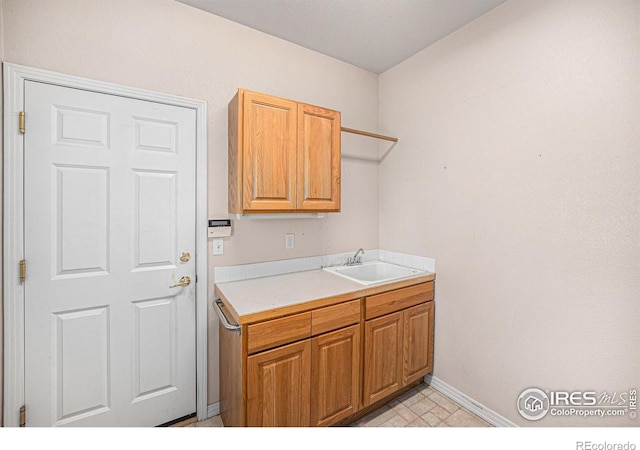 laundry room featuring baseboards and a sink