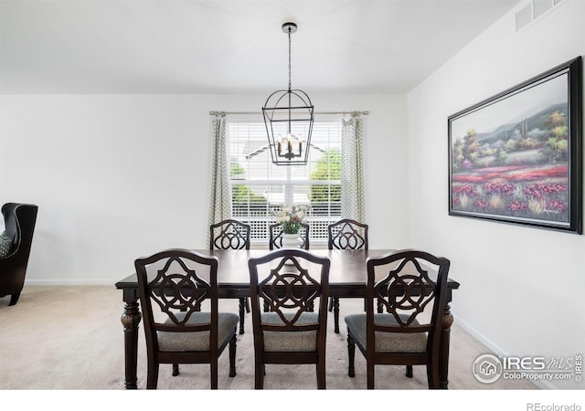 carpeted dining space with a chandelier and baseboards