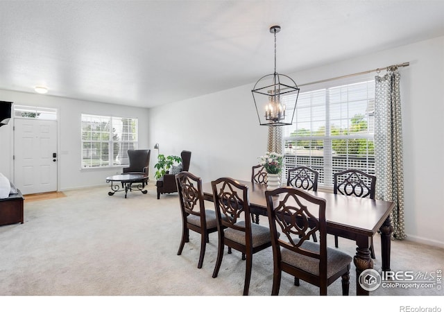 dining area with a chandelier, baseboards, and light colored carpet
