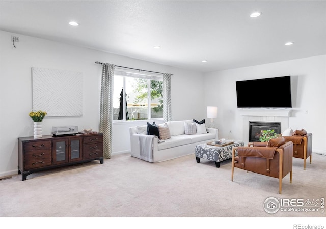 living area featuring light carpet, recessed lighting, a fireplace, and baseboards