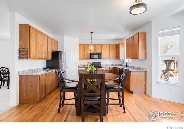 kitchen with black microwave, a sink, light wood-style flooring, and electric range