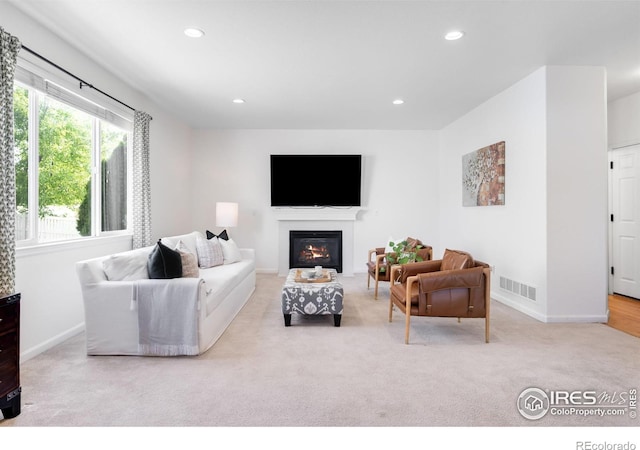 living area with carpet, baseboards, recessed lighting, and a glass covered fireplace