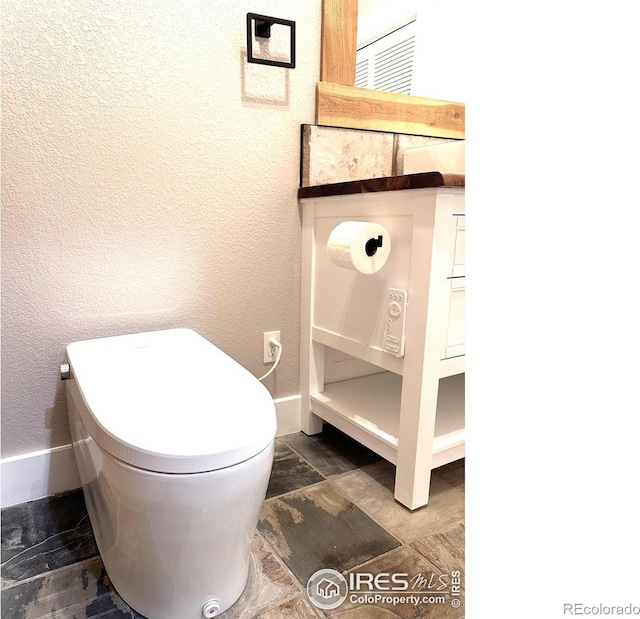 5620 Fossil Creek Pkwy Unit 4106, Fort Collins, CO 80525 - bathroom featuring baseboards, stone finish flooring, a textured wall, and toilet