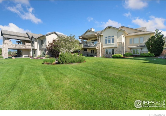 6701 Clovis Ct, Timnath, CO 80547 - back of house featuring a balcony, a yard, stucco siding, stone siding, and a chimney