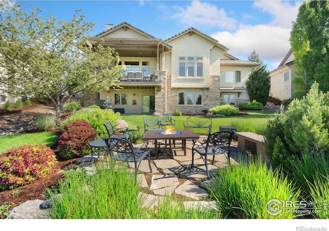 6701 Clovis Ct, Timnath, CO 80547 - back of house featuring a balcony, a patio, stucco siding, a yard, and stone siding