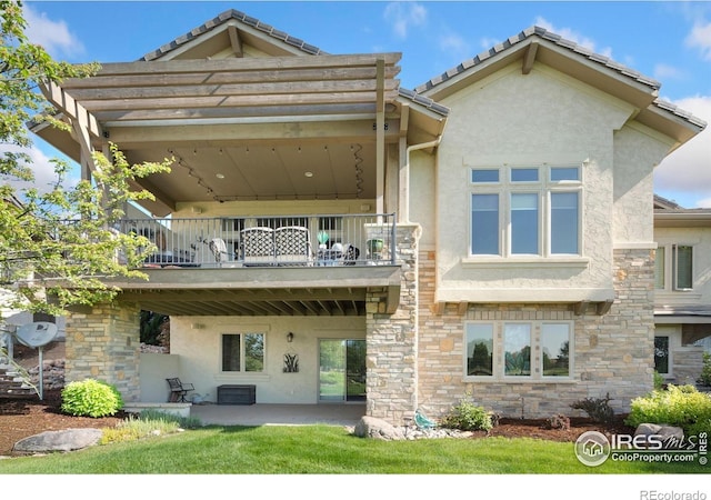 6701 Clovis Ct, Timnath, CO 80547 - back of property with a balcony, stucco siding, stone siding, and a patio area