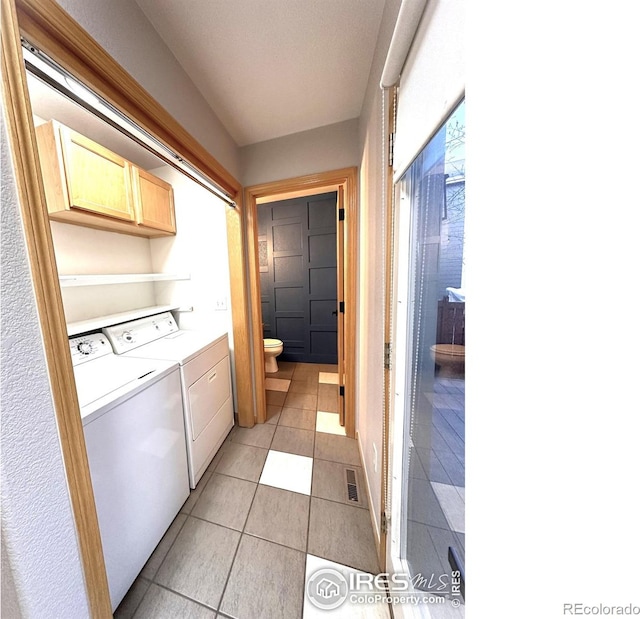 laundry area with cabinet space, separate washer and dryer, and light tile patterned floors