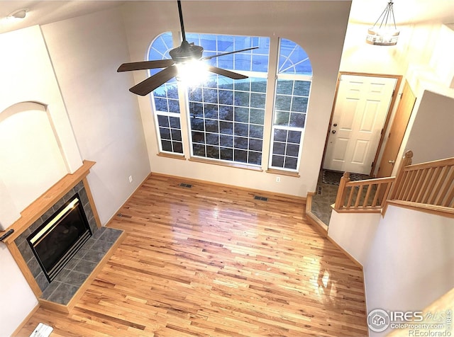 unfurnished living room with wood finished floors, a ceiling fan, and a tile fireplace