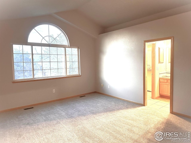 unfurnished room with light carpet, lofted ceiling, and baseboards