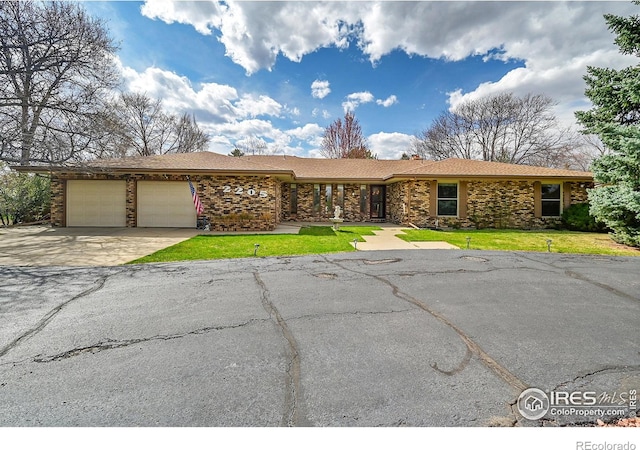 view of front of home with an attached garage, driveway, stone siding, and a front lawn