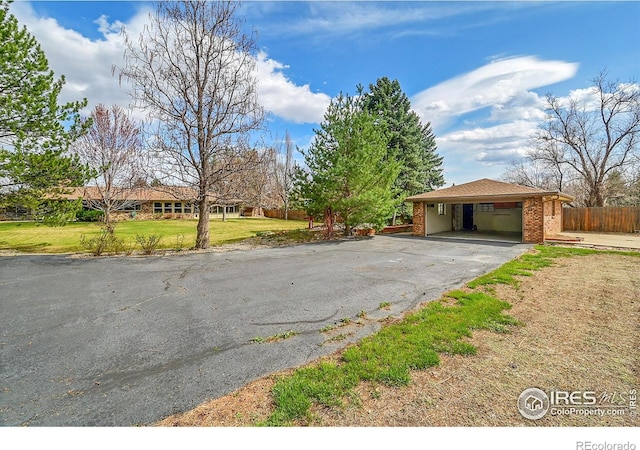 exterior space with a front yard, fence, brick siding, driveway, and an attached carport