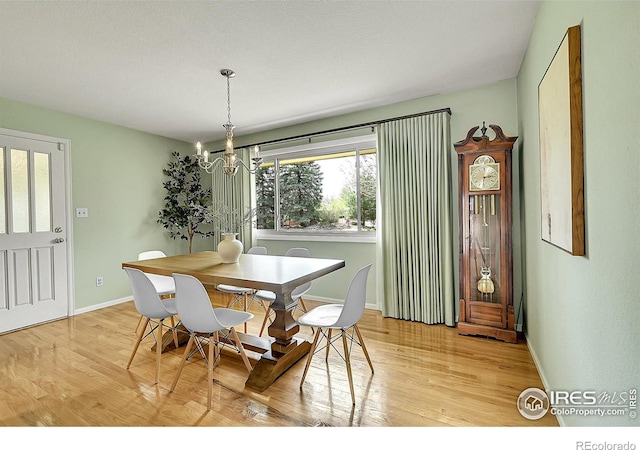 dining room with light wood-type flooring, an inviting chandelier, and baseboards
