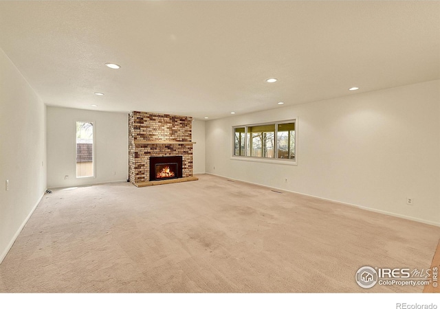unfurnished living room with light colored carpet, baseboards, a brick fireplace, and recessed lighting