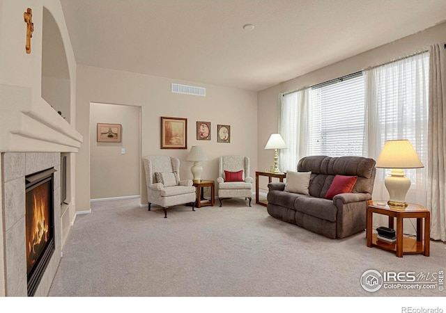 carpeted living room with a tiled fireplace, visible vents, and baseboards
