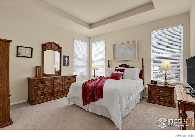 bedroom featuring a tray ceiling, baseboards, and light colored carpet