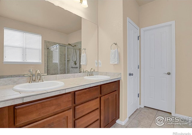 bathroom featuring a stall shower, double vanity, a sink, and tile patterned flooring