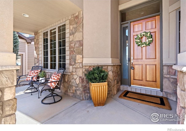 6741 Bandon Dunes Dr, Windsor, CO 80550 - doorway to property featuring stone siding and covered porch