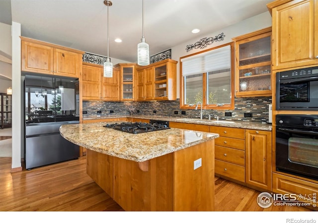 6741 Bandon Dunes Dr, Windsor, CO 80550 - kitchen with light stone counters, a center island, decorative backsplash, light wood finished floors, and black appliances
