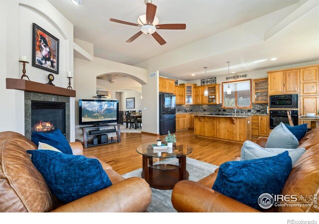 6741 Bandon Dunes Dr, Windsor, CO 80550 - living area featuring light wood-type flooring, recessed lighting, a fireplace, a ceiling fan, and arched walkways
