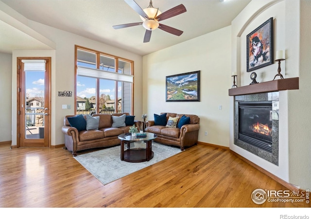 6741 Bandon Dunes Dr, Windsor, CO 80550 - living area with baseboards, wood finished floors, a tile fireplace, and a ceiling fan