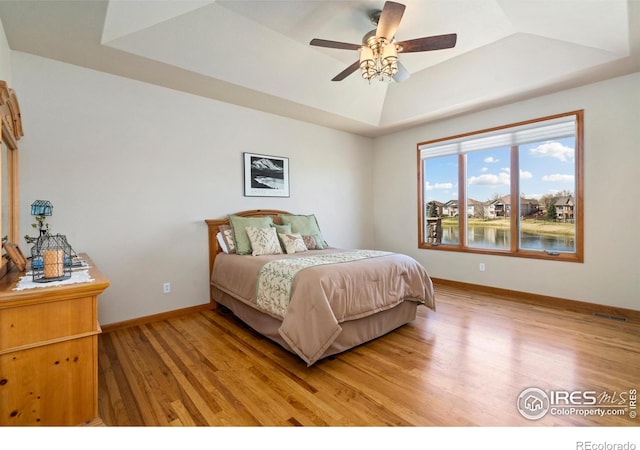 6741 Bandon Dunes Dr, Windsor, CO 80550 - bedroom with light wood-style flooring, a raised ceiling, ceiling fan, and baseboards