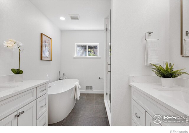 545 S Harrison Ln, Denver, CO 80209 - bathroom featuring visible vents, a freestanding tub, tile patterned flooring, two vanities, and a sink