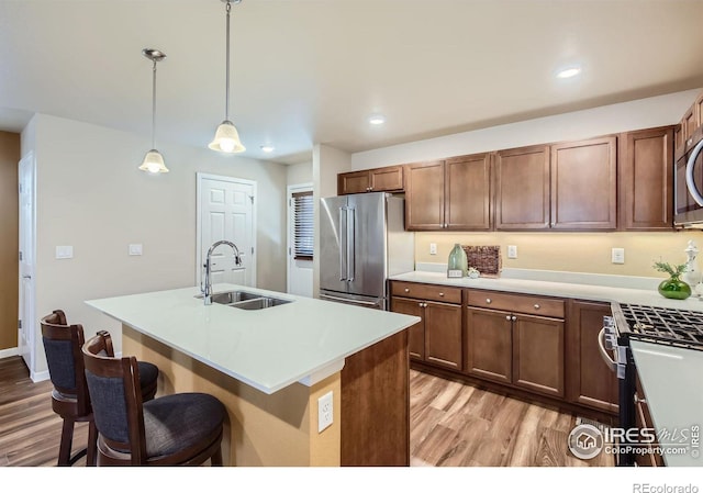 61 Avocet Ct, Longmont, CO 80501 - kitchen with a sink, appliances with stainless steel finishes, light wood-style flooring, a breakfast bar area, and light countertops