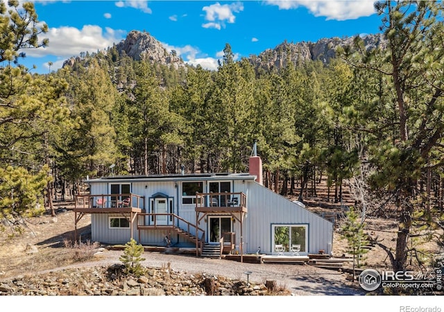 712 Aspen Dr, Lyons, CO 80540 - view of front facade with a view of trees, a chimney, and a deck