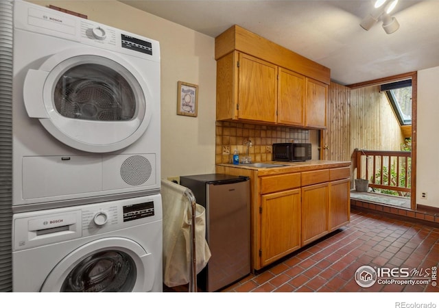712 Aspen Dr, Lyons, CO 80540 - laundry area with brick floor, laundry area, a sink, and stacked washer and clothes dryer