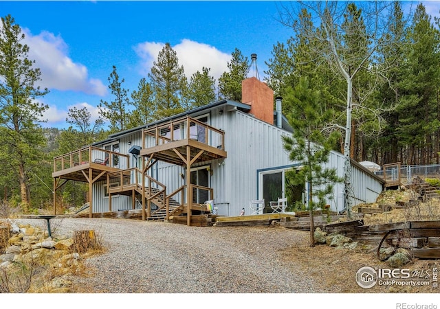 712 Aspen Dr, Lyons, CO 80540 - back of property with board and batten siding, a deck, and a chimney