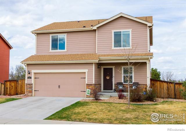 view of front of house featuring an attached garage, concrete driveway, a front yard, and fence