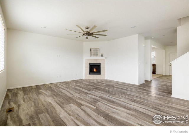 9283 Sedalia St, Commerce City, CO 80022 - unfurnished living room with a tile fireplace, visible vents, wood finished floors, and ceiling fan
