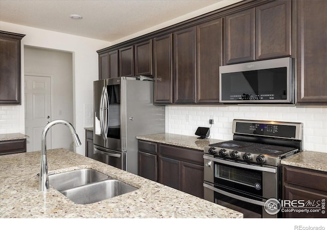 9283 Sedalia St, Commerce City, CO 80022 - kitchen with tasteful backsplash, dark brown cabinetry, a sink, and appliances with stainless steel finishes